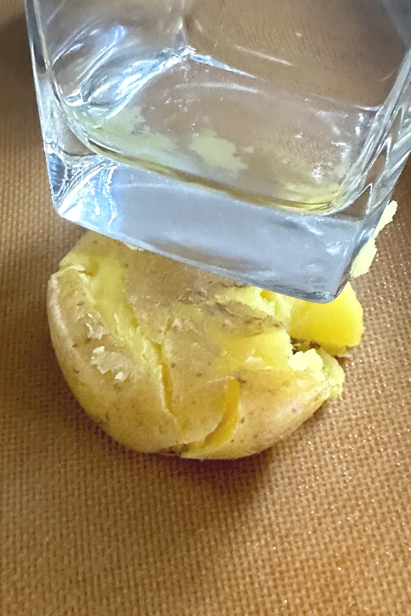 smashing a Yukon gold with the bottom of a glass 
