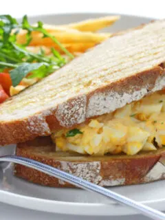deviled egg salad sandwich, tomatoes and french fries on plate