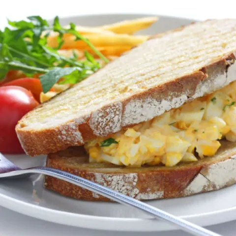 deviled egg salad sandwich, tomatoes and french fries on plate