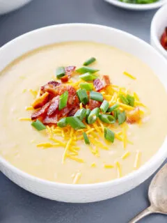 crock pot potato soup garnished with cheese, bacon and green onions
