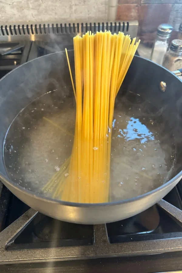 spaghetti noodles going into boiling water